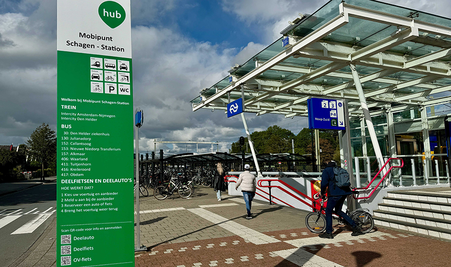 Openbaar vervoer station waar trein en bus samenkomen. Ook zijn er deelfietsen en auto's.