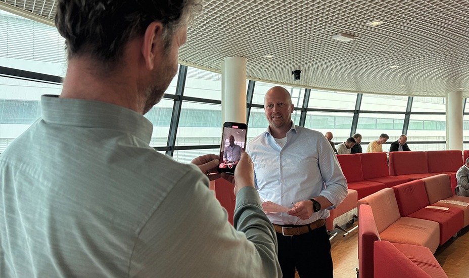 Man houdt mobiel in de hand om een ondernemer te filmen die een pitch oefent.
