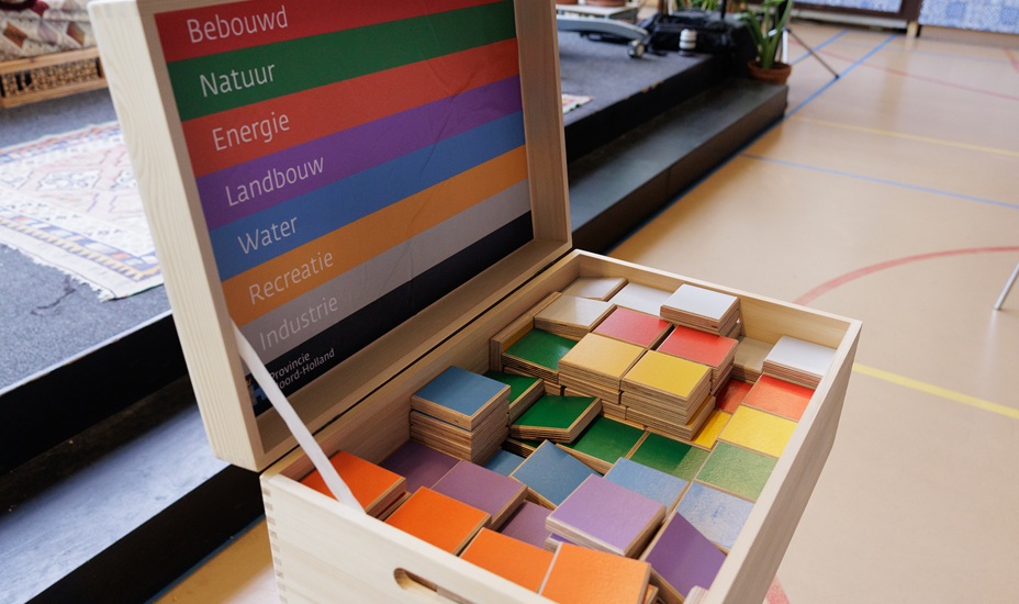 Doos met gekleurde blokken die passen bij de verschillende thema's van Regie op de Ruimte.