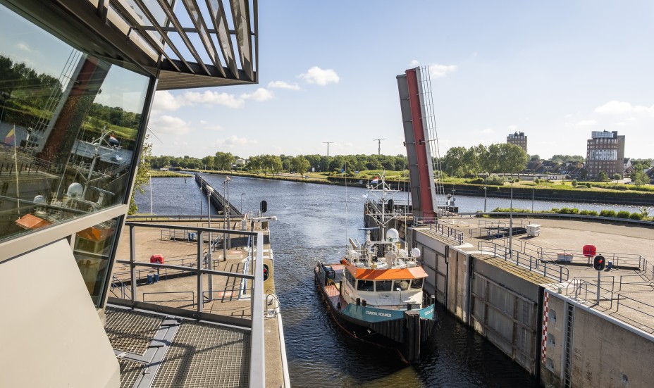 Schip vaart door Koopvaardersschutsluis met bedienhuis op de voorgrond